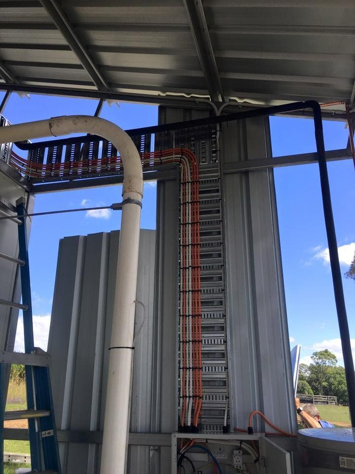 A Ladder is Hanging From the Side of a Building Next to a Pipe — Himec Electrical In Murphy's Creek, QLD