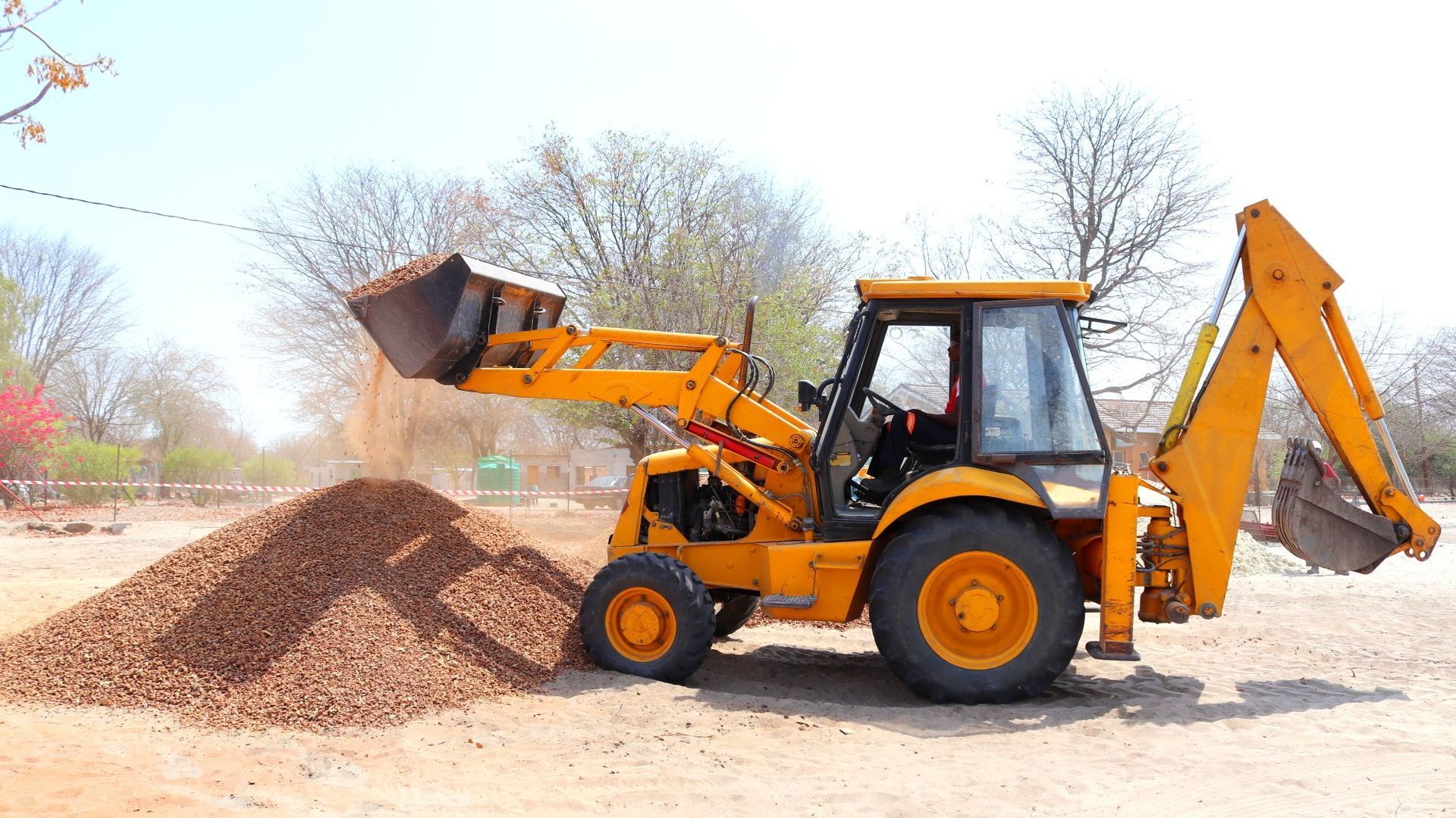 A couple of construction vehicles are driving through a pile of dirt.
