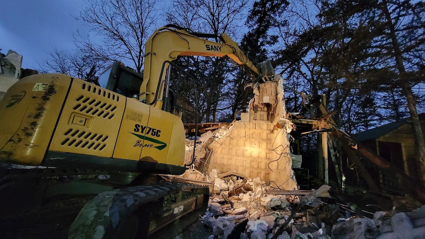 A large yellow excavator is demolishing a house.