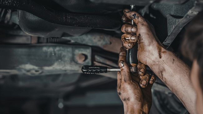 a mechanic with greasy hands doing an auto repair
