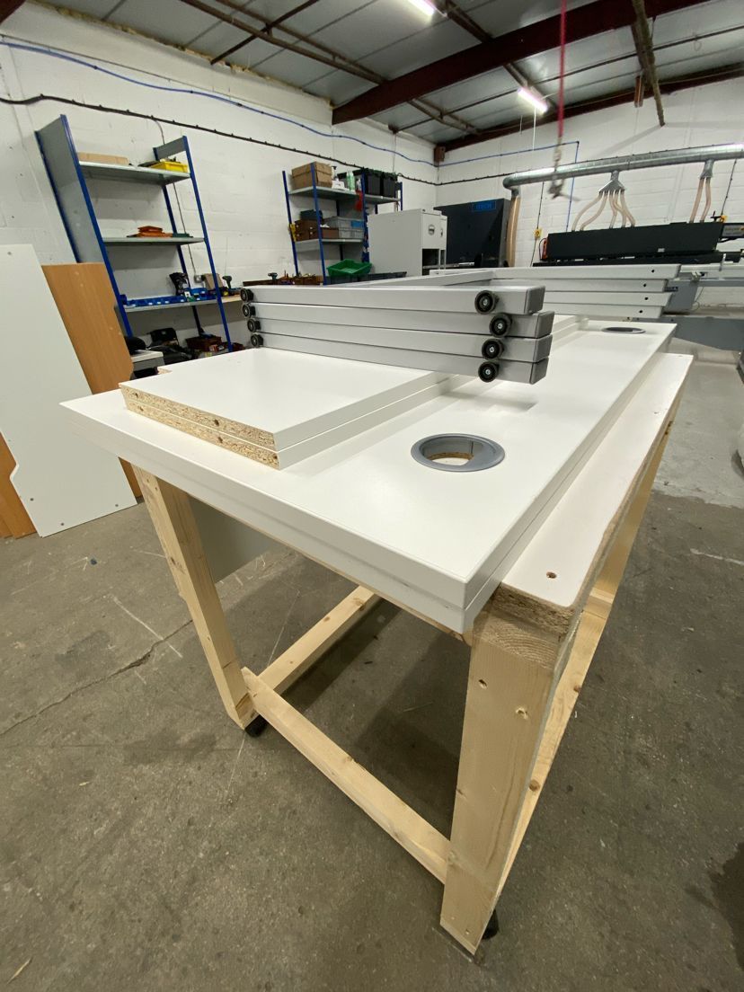 White tabletop with materials, on a wooden workbench in a workshop.