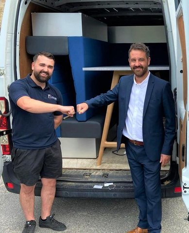 A Coggin SOS team member and Burnley FC in the Community shaking hands at the back of a van loaded with soft seating and tables