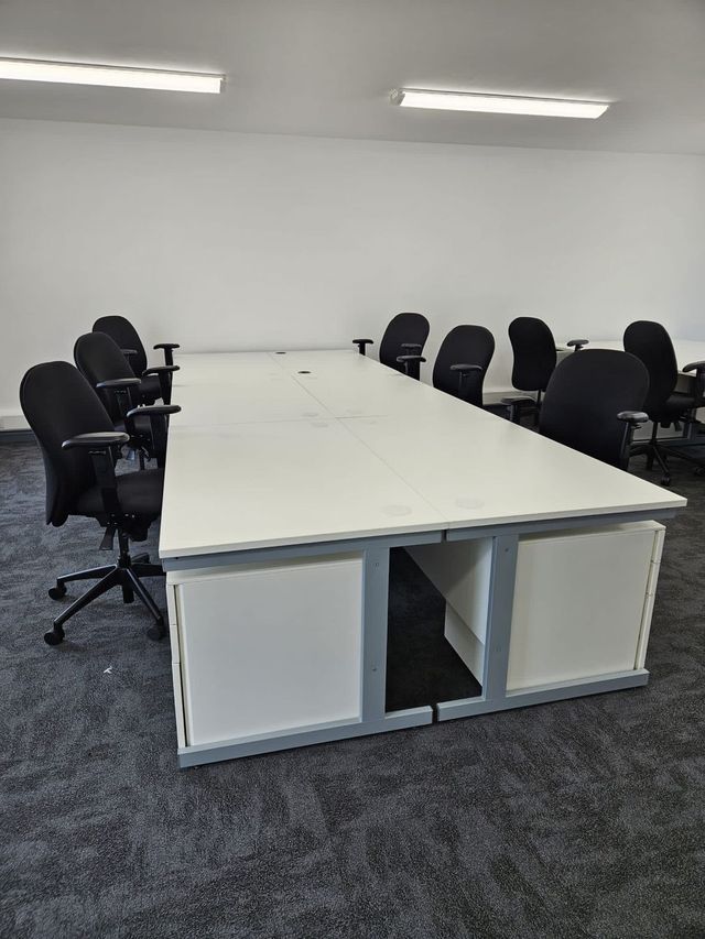 A back to back bank of refurbished white desks with under desk pedestals and task chairs