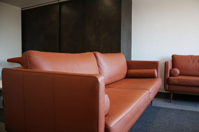 Refurbished tan leather sofa and armchair in an office breakout area