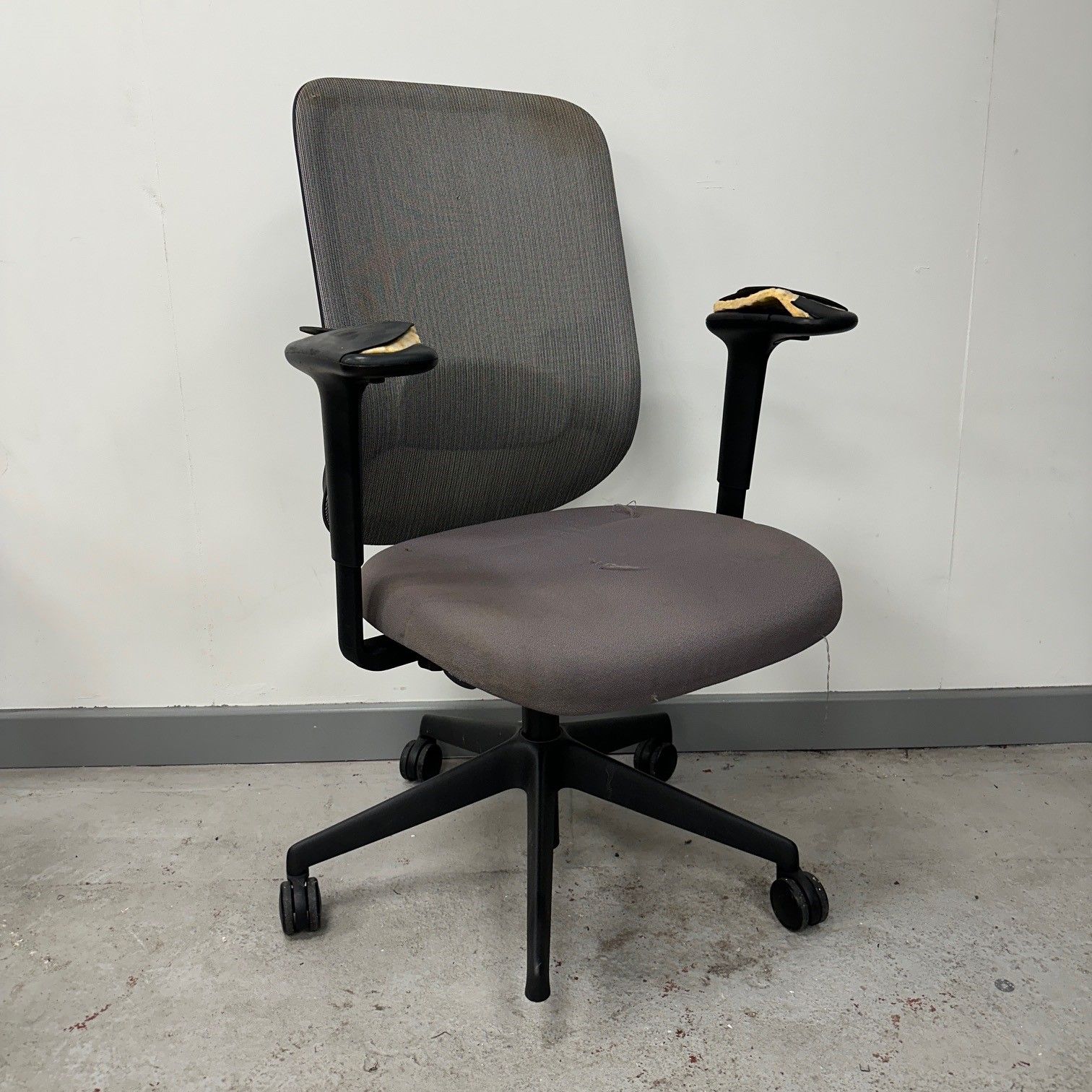 Gray office chair with worn fabric, black arms, and a five-star base with wheels.