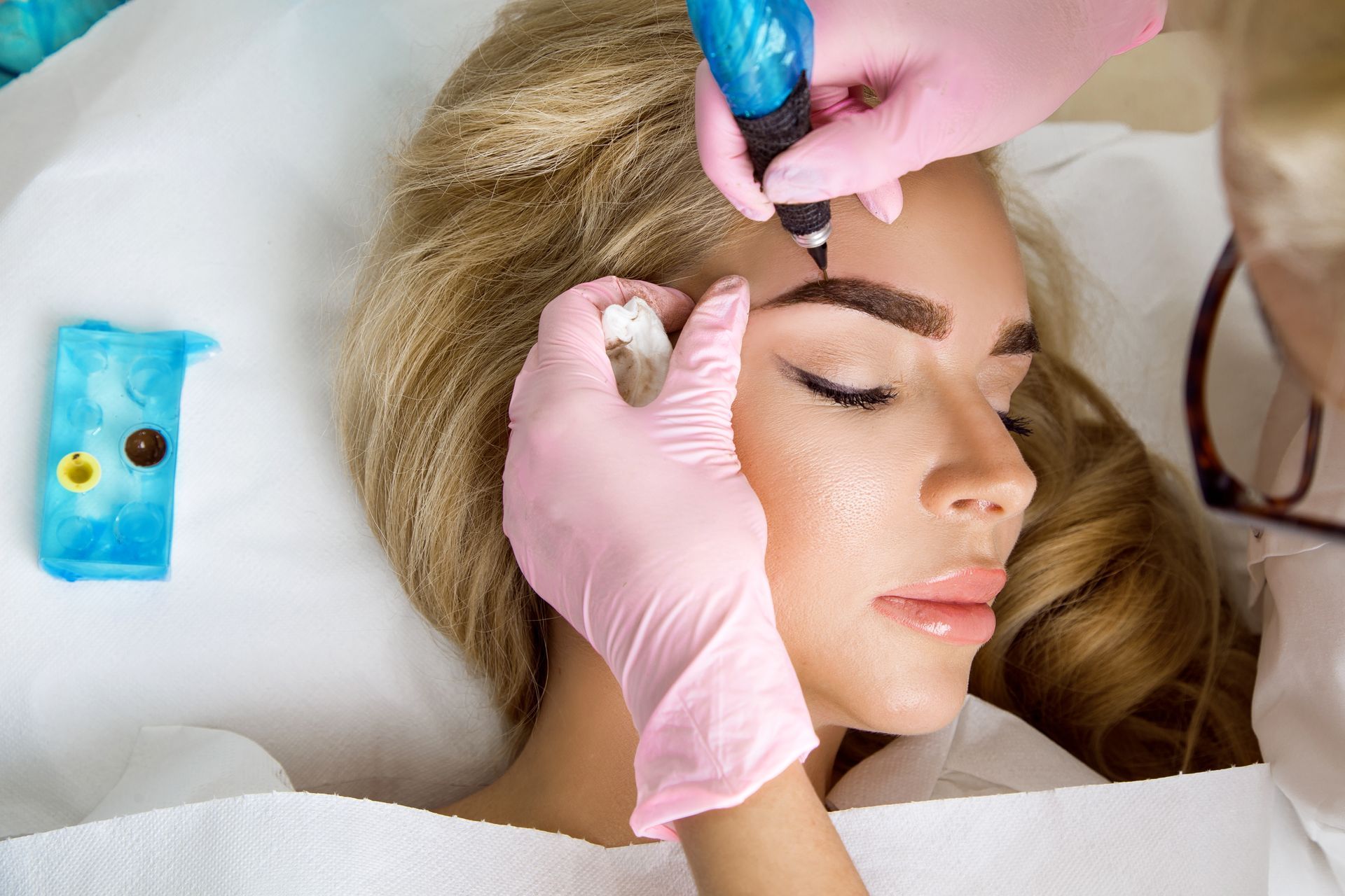 A woman is getting a tattoo on her eyebrows.