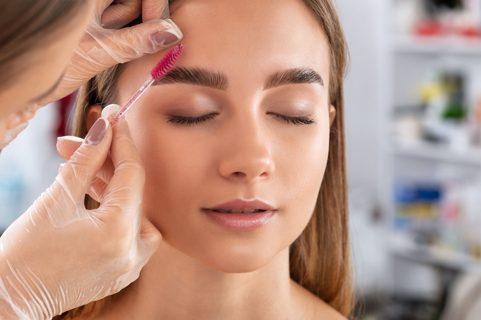 A woman is getting her eyebrows done by a makeup artist.