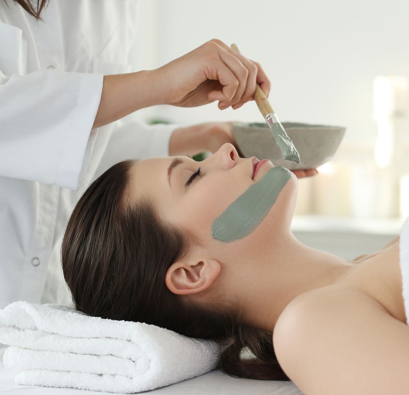 A woman is getting a facial treatment with a brush