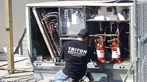 Technician inspecting electrical equipment inside an open utility cabinet outdoors