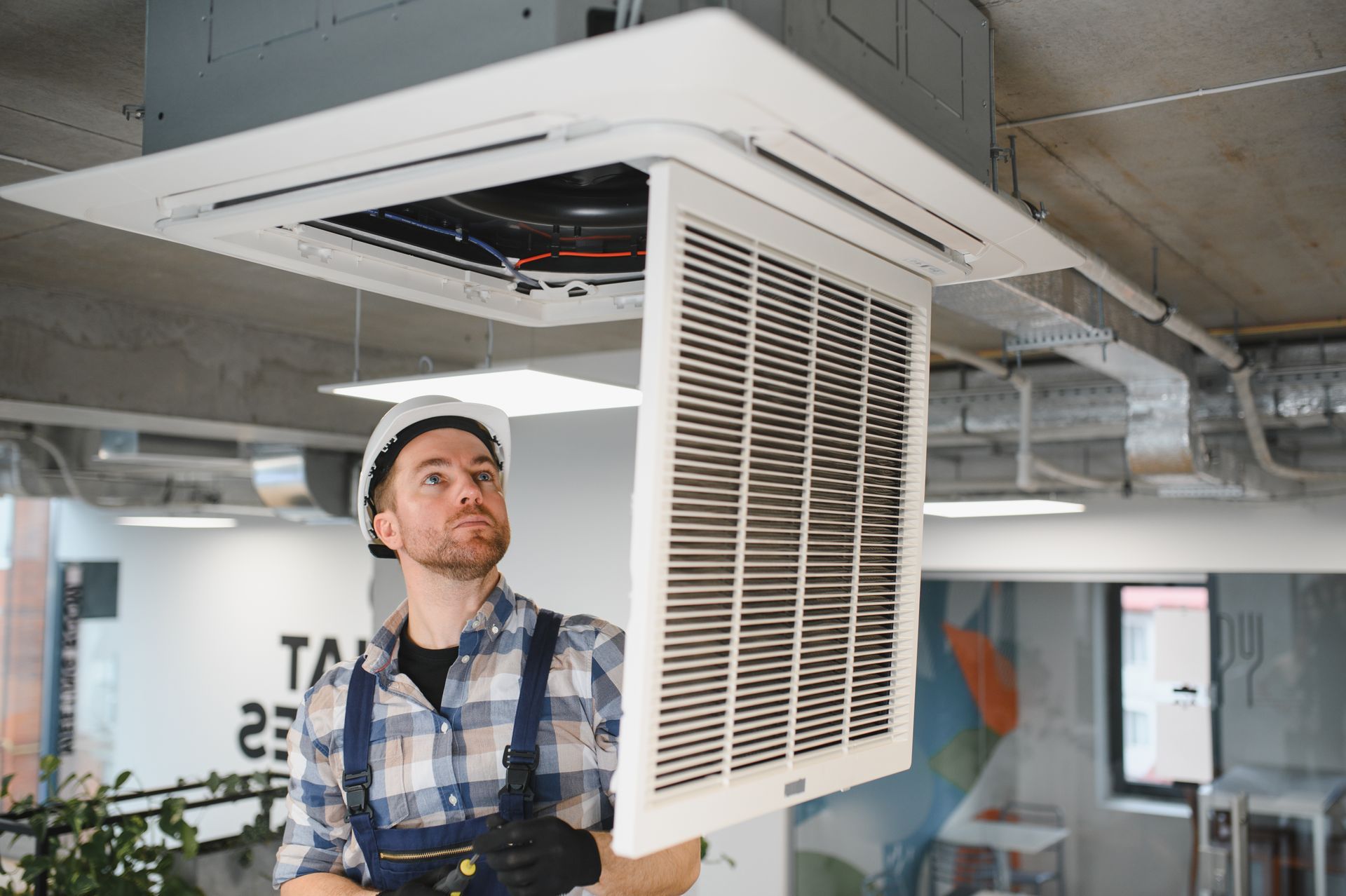 HVAC technician installing air conditioning ventilation system.