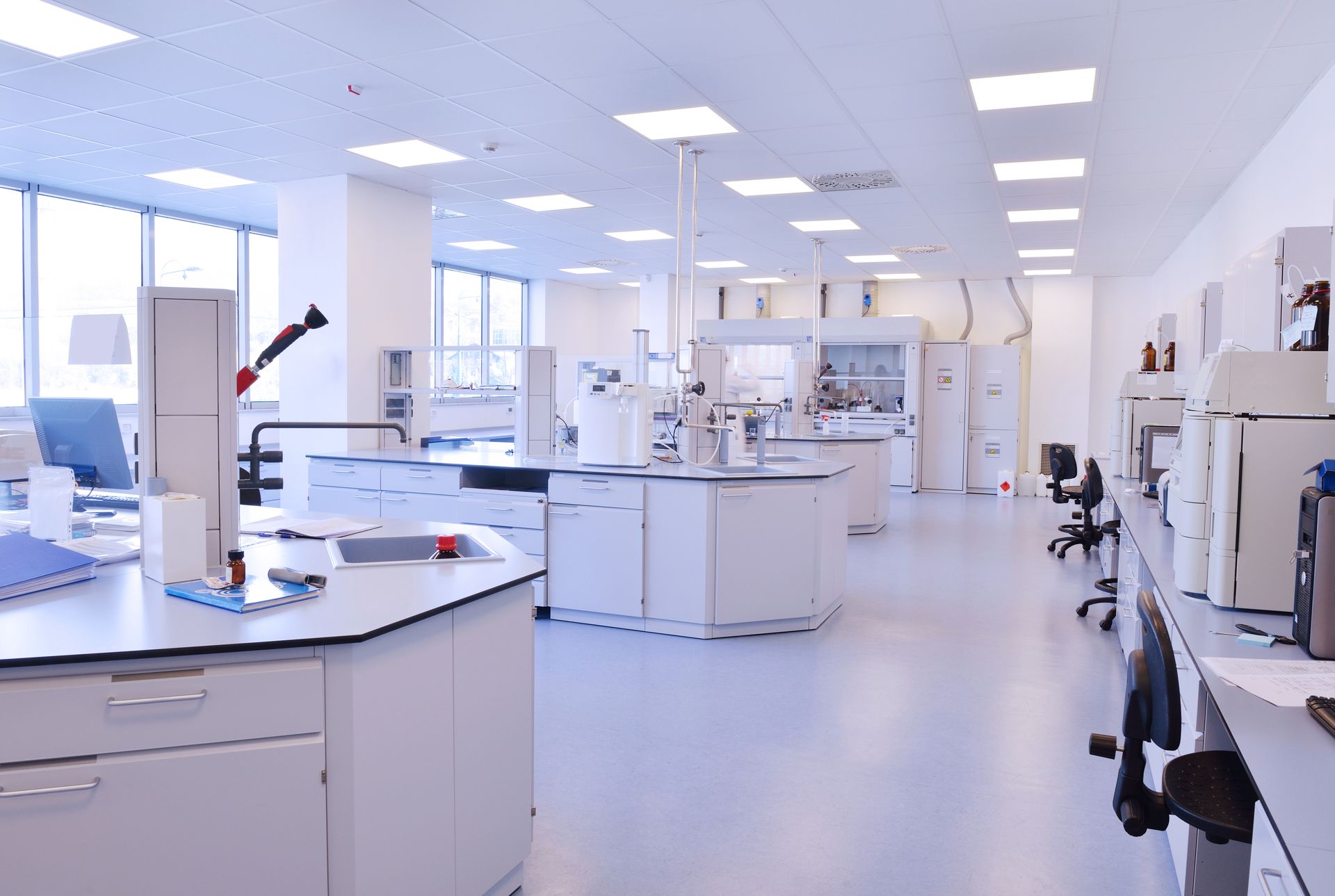 Three outdoor air conditioning units beside a beige house and green lawn