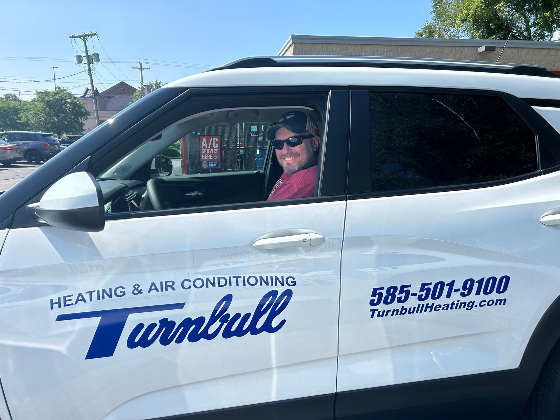 Man in a white Turnbull Heating & Air Conditioning truck, smiling.