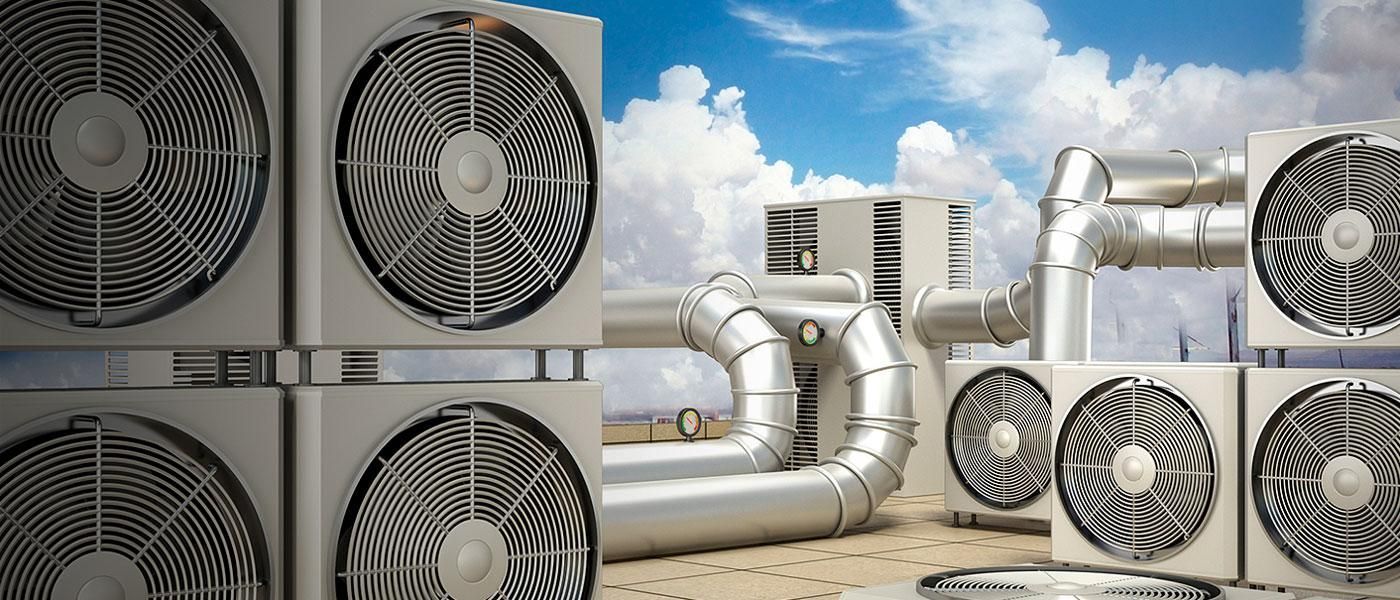 Rooftop HVAC units with fans, ductwork, and a blue sky with clouds.