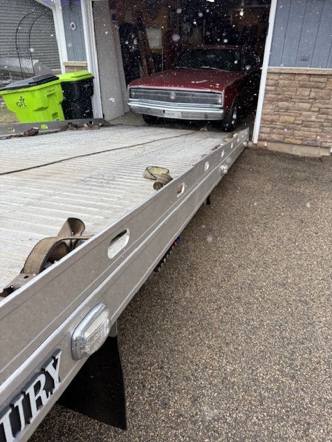 A burgundy car being loaded onto a tow truck ramp in a driveway. A burgundy car being loaded onto a tow truck ramp in a driveway.