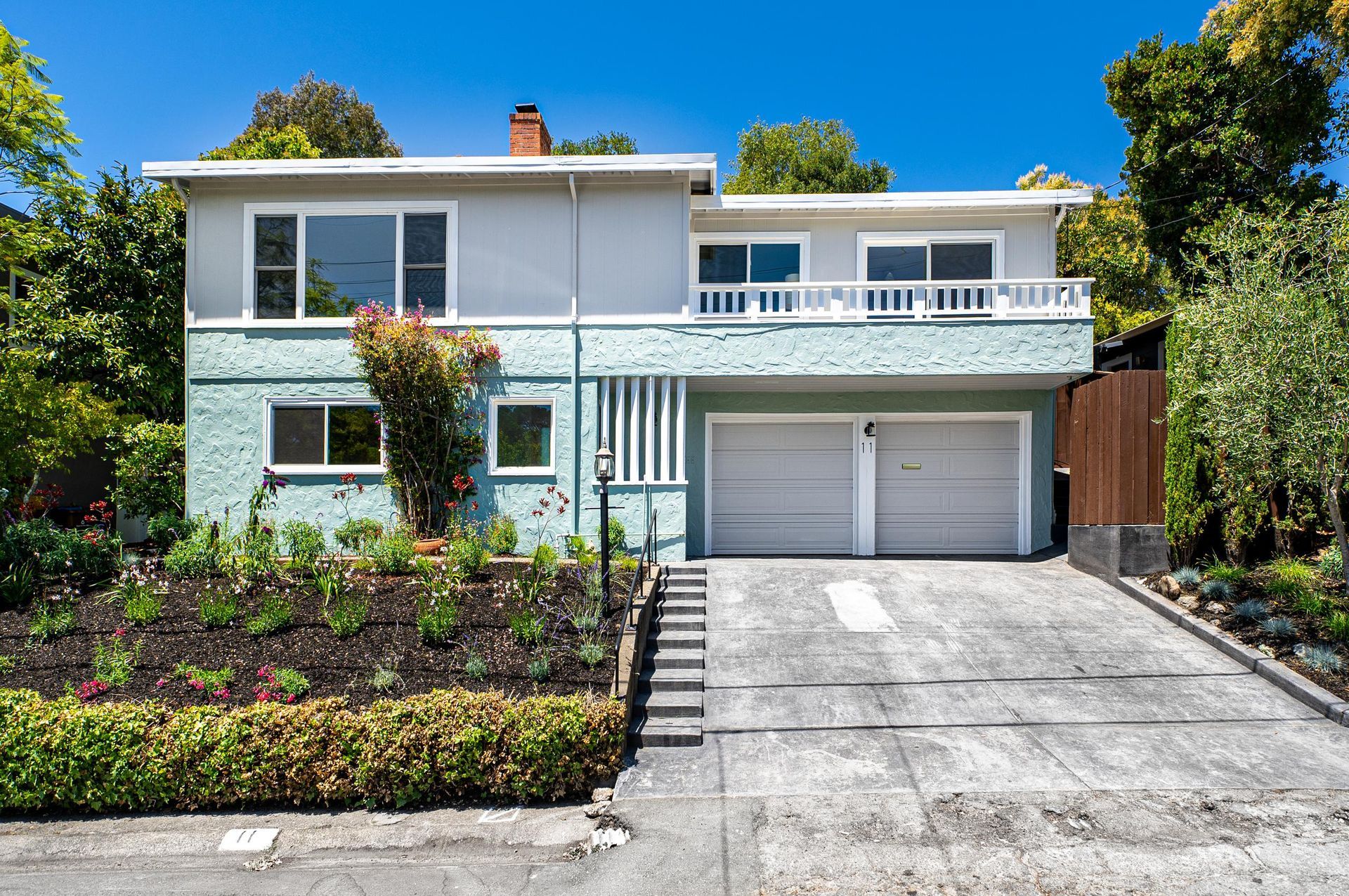 Two-story white house with a double garage, driveway, and landscaped front yard under a blue sky