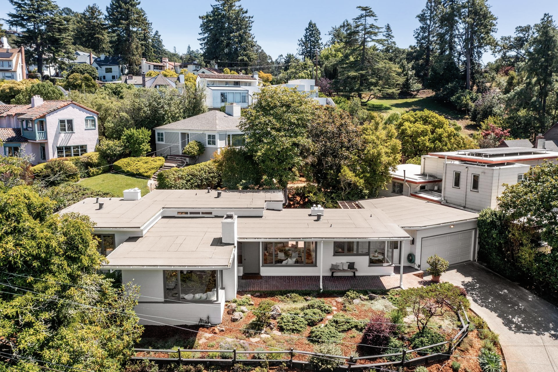 Aerial view of a modern hillside home surrounded by lush trees and gardens