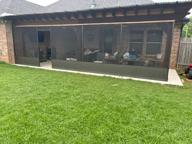 Backyard patio with a covered seating area and large grassy lawn