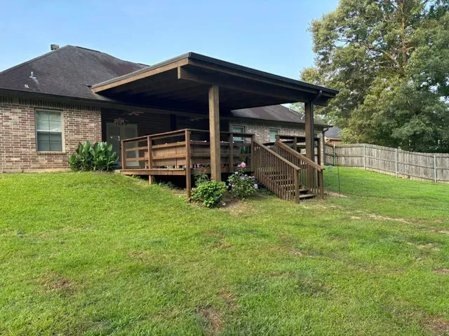 Suburban house with covered wooden porch and stairs on a grassy lawn under a blue sky