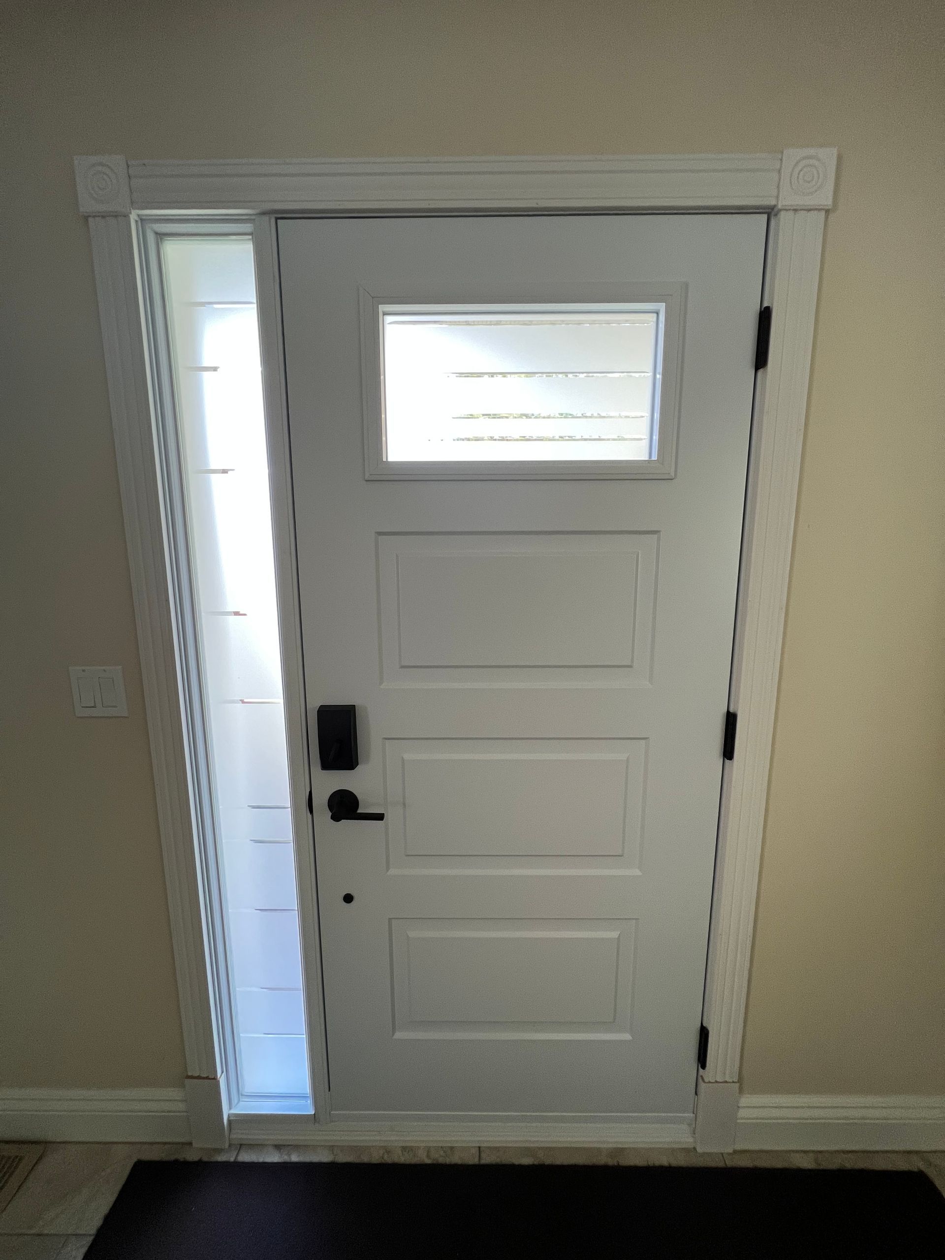 White front door with frosted side panel and small window above a black handle and lock.