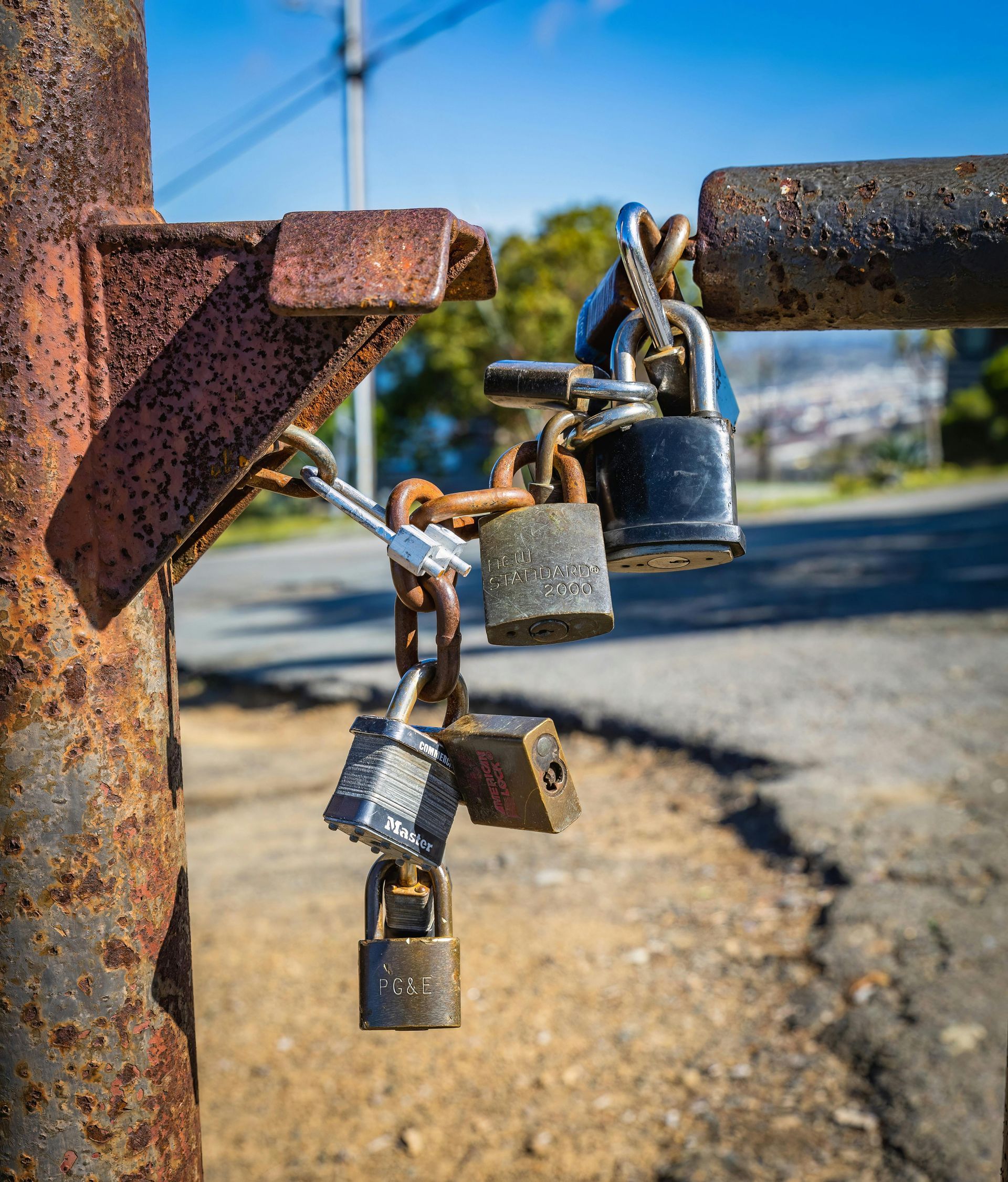 A bunch of padlocks hanging from a rusty pole