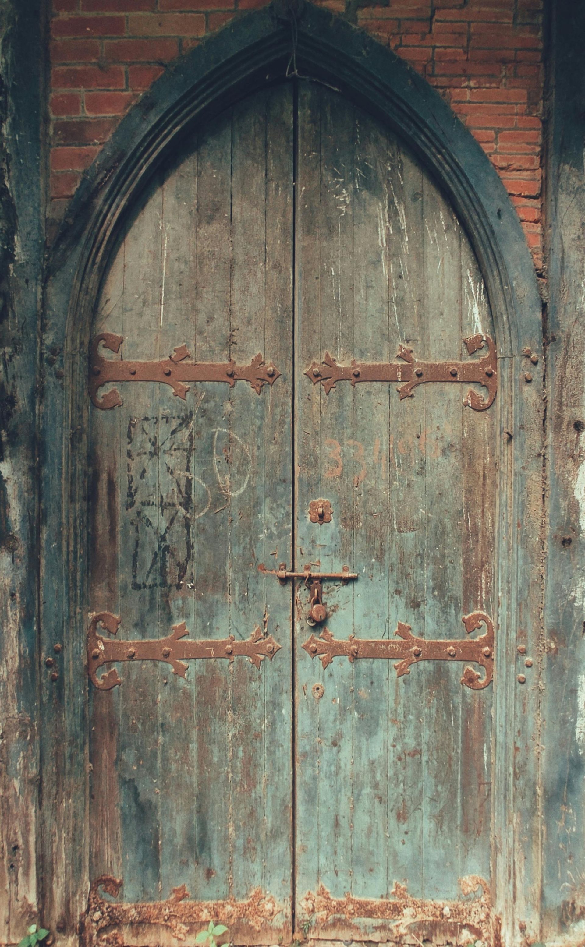 An old wooden door with a brick wall behind it.