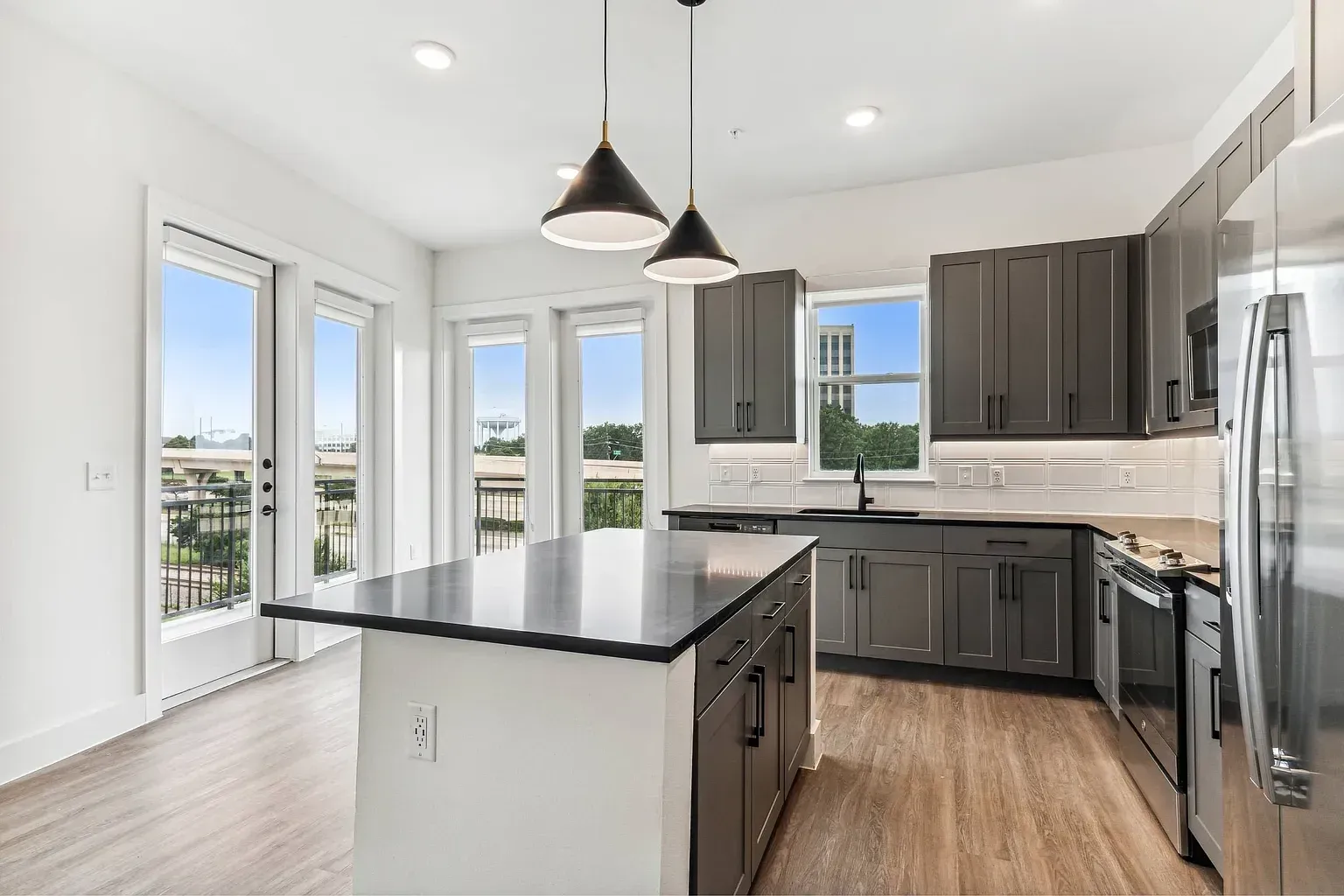 Modern kitchen with gray cabinets, a large island, and stainless steel appliances.