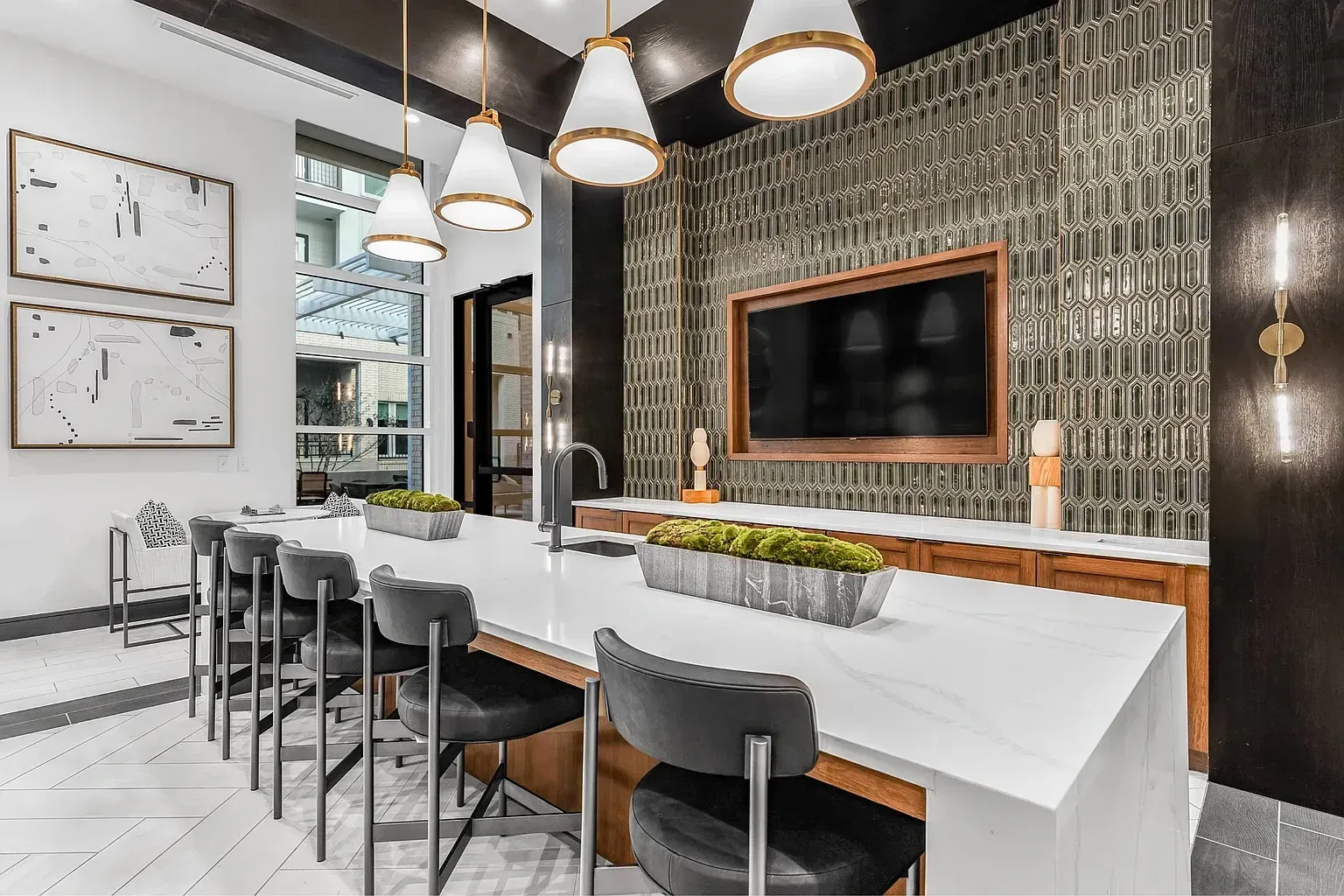 Modern communal kitchen island with bar stools and a mounted TV.