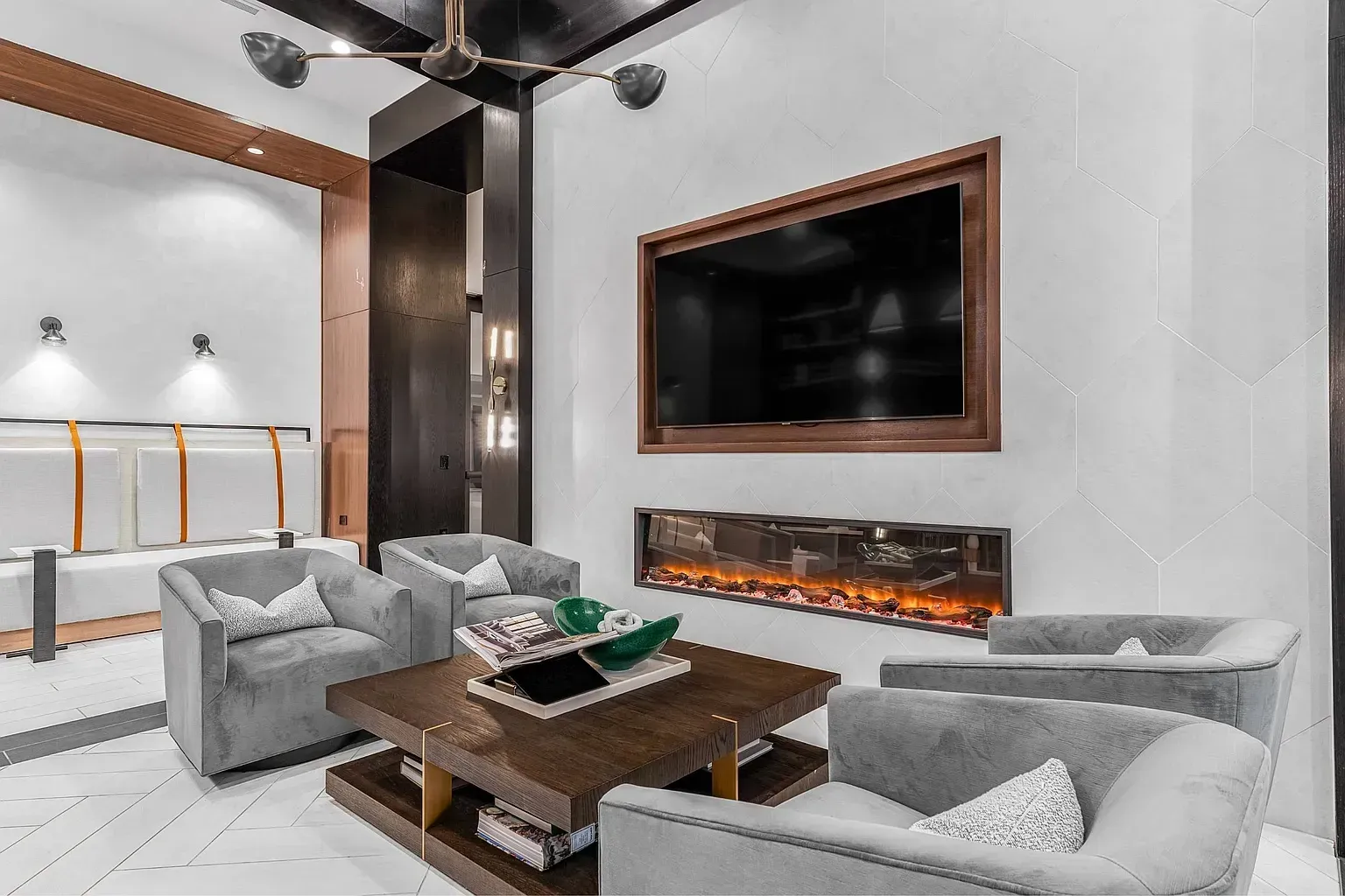 Comfortable seating area with plush chairs, a modern fireplace, and a wall-mounted TV.