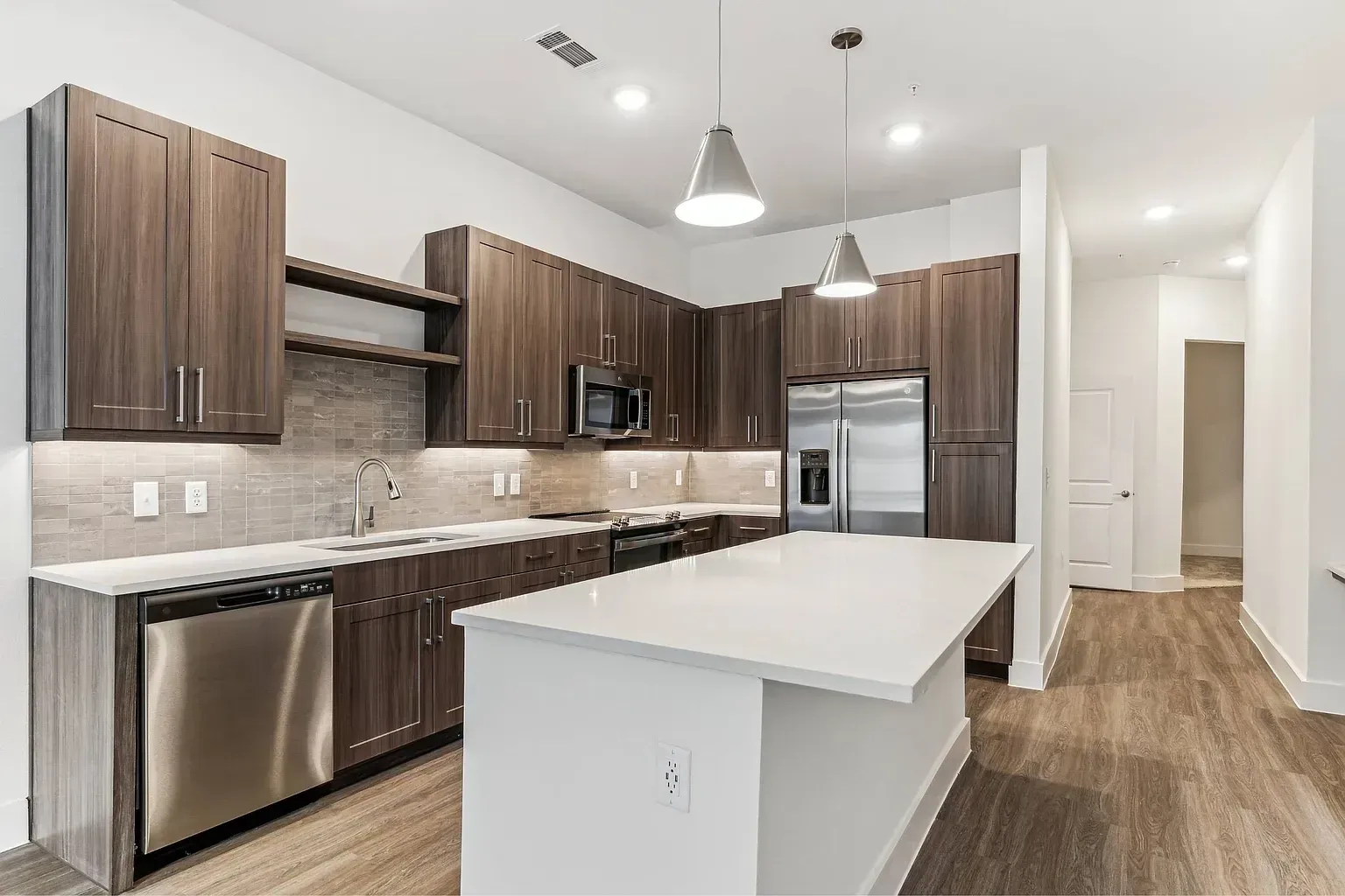 Modern kitchen with dark wood cabinets, stainless steel appliances, and a large island.