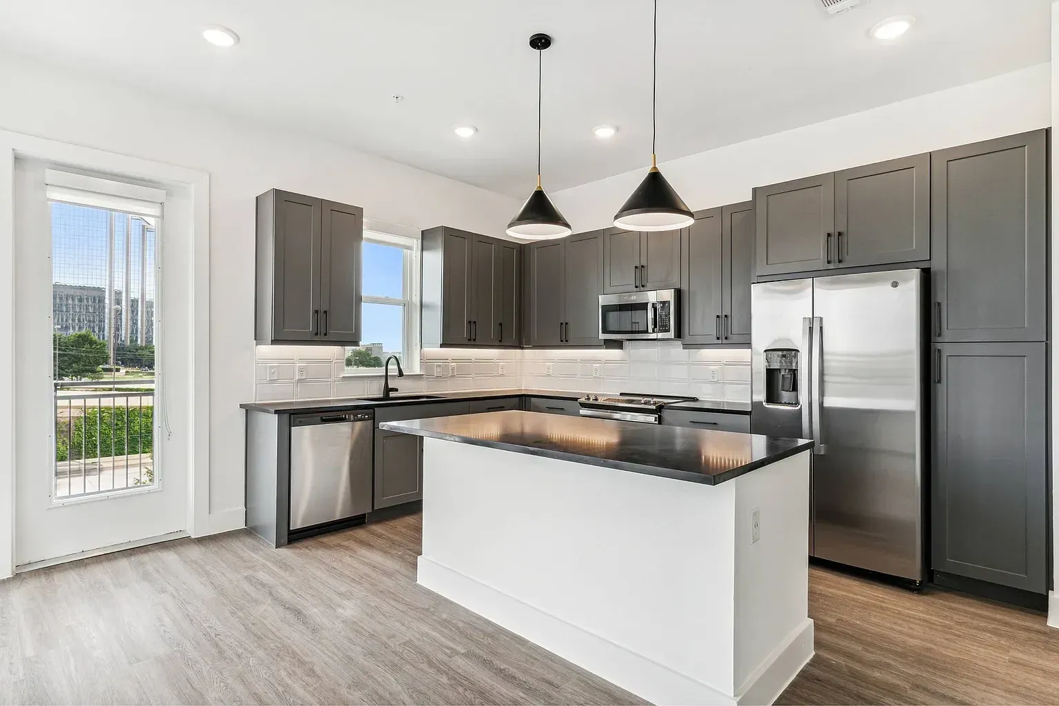 Modern kitchen with dark gray cabinets, stainless steel appliances, and an island.