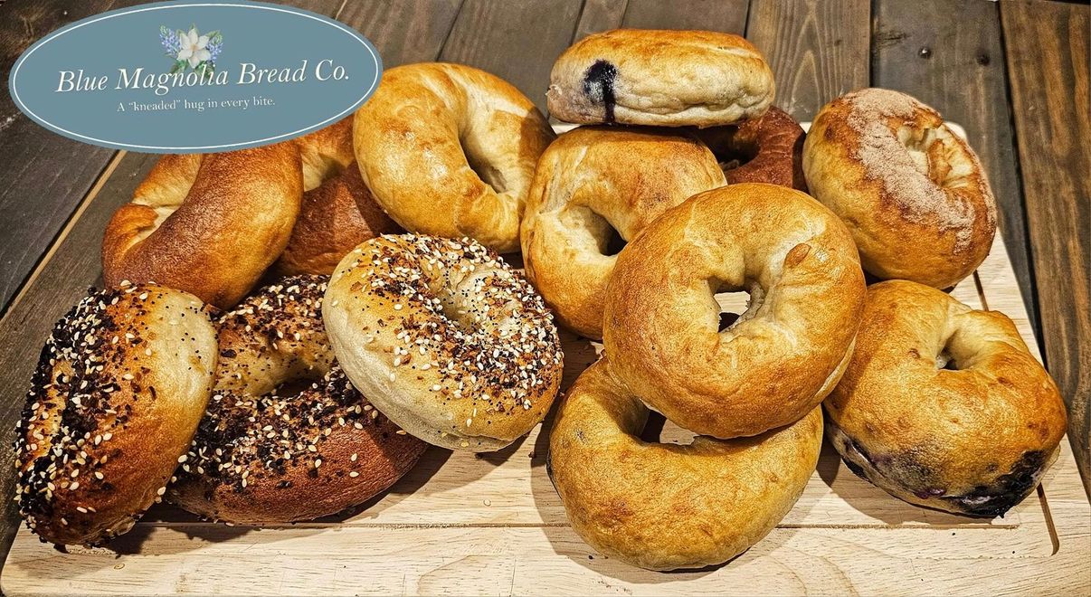 A bunch of bagels are sitting on a wooden cutting board