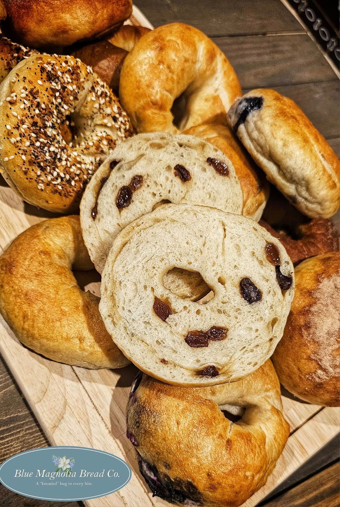 A variety of bagels are sitting on a wooden cutting board.