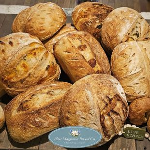 A bunch of loaves of bread are sitting on a wooden table.
