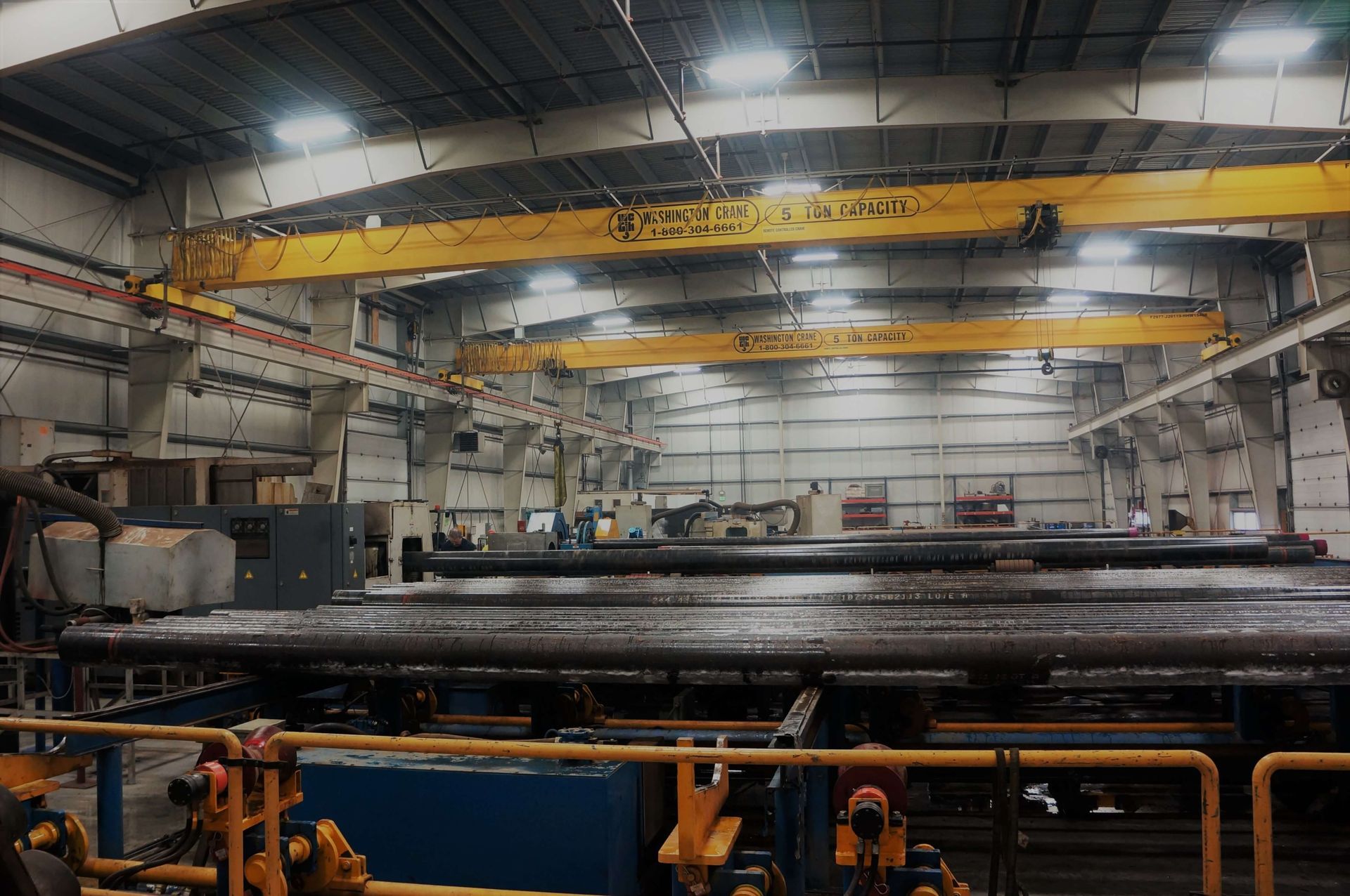 A large warehouse filled with lots of pipes and cranes.