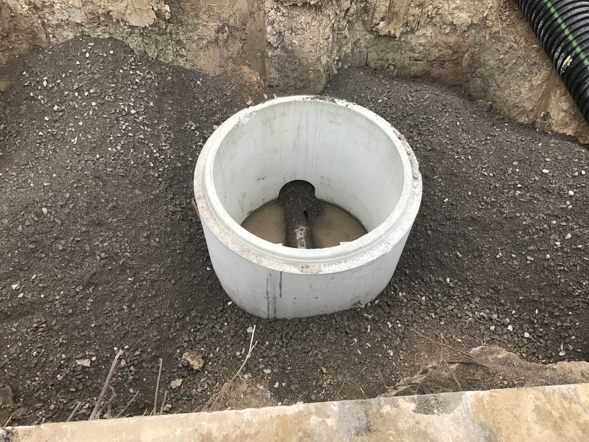 A white pipe is sitting in the dirt next to a pipe.
