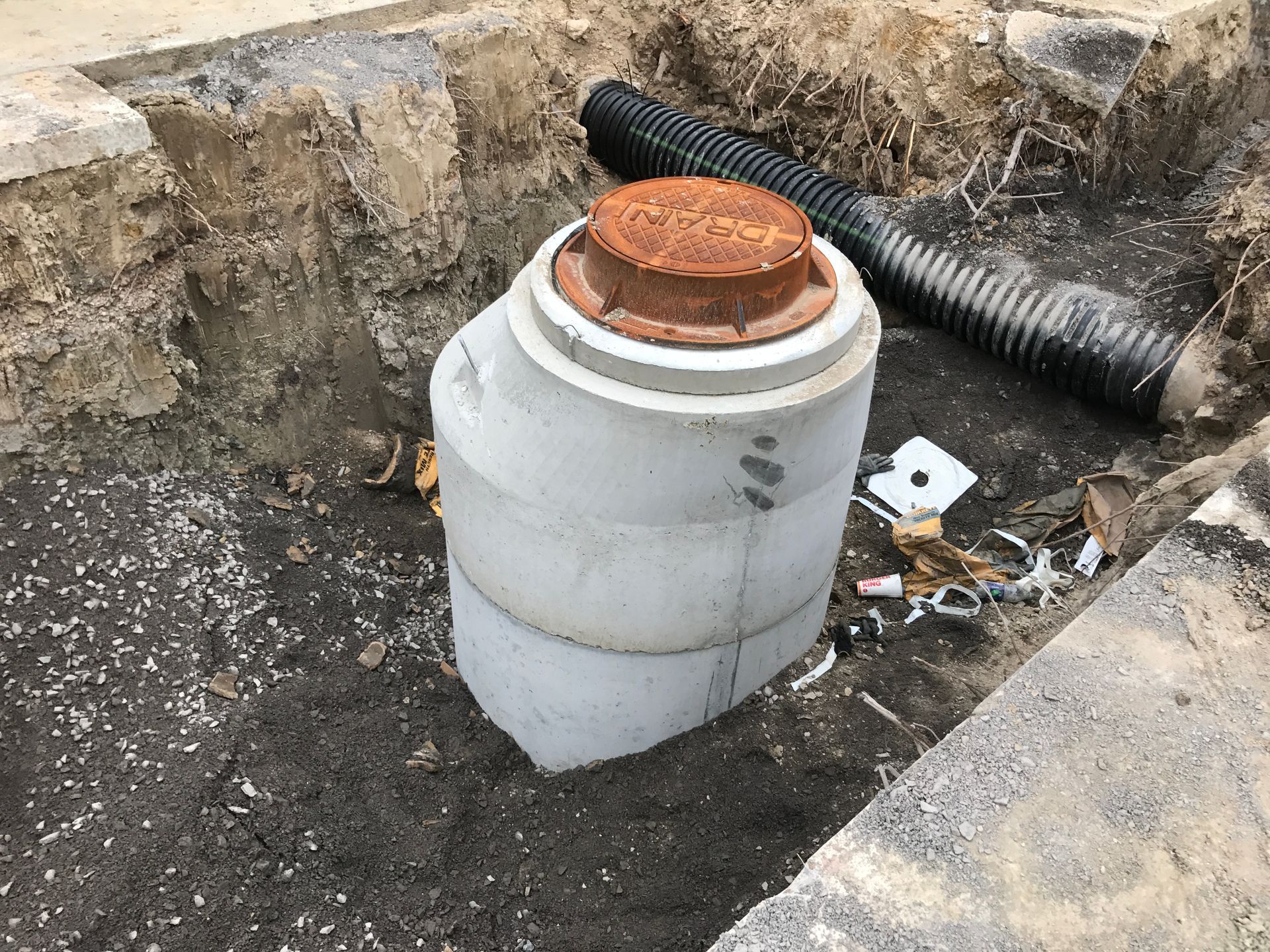 A white pipe with a rusty lid is sitting in the dirt.