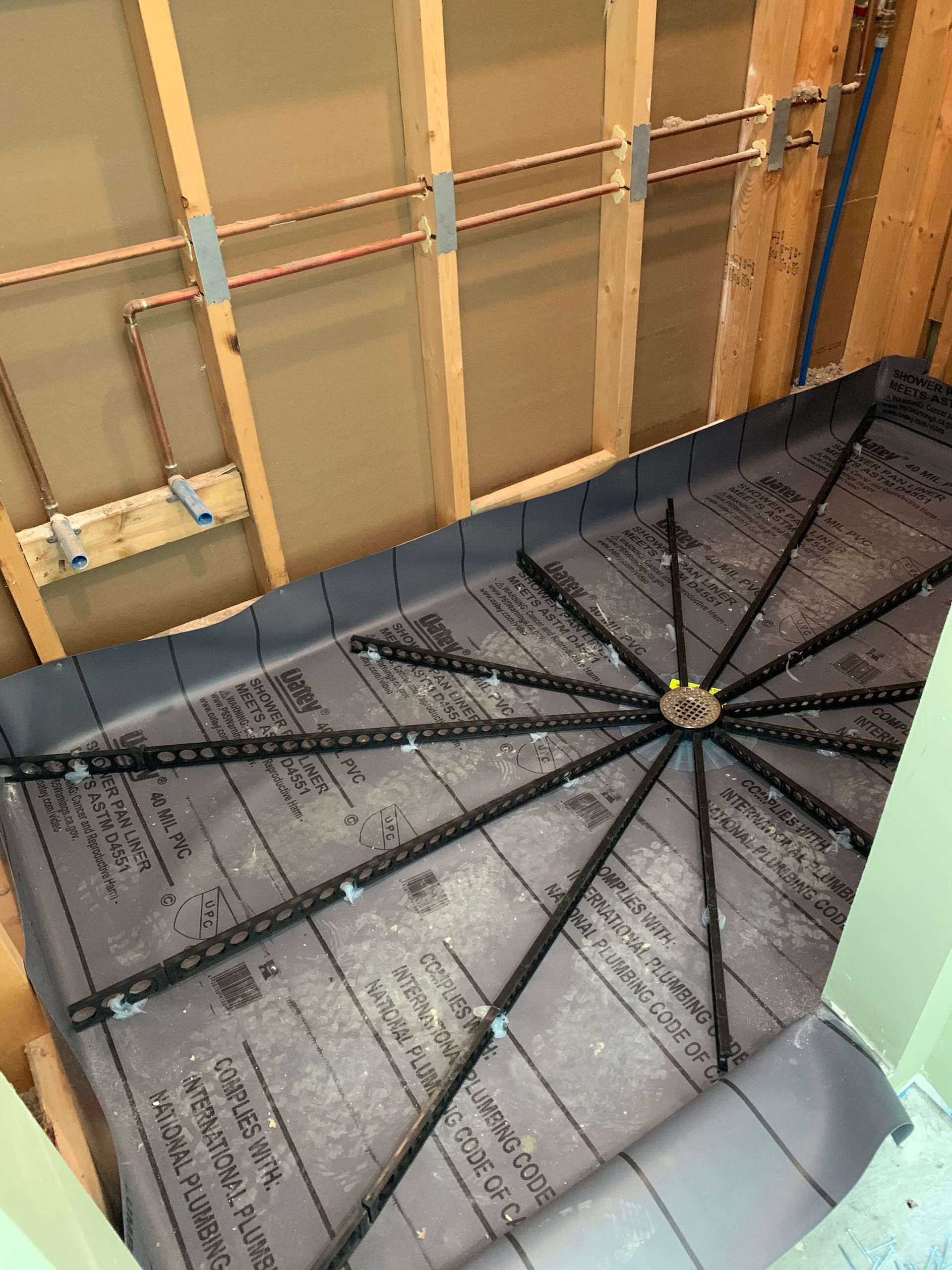 The floor of a bathroom is being remodeled with copper pipes.