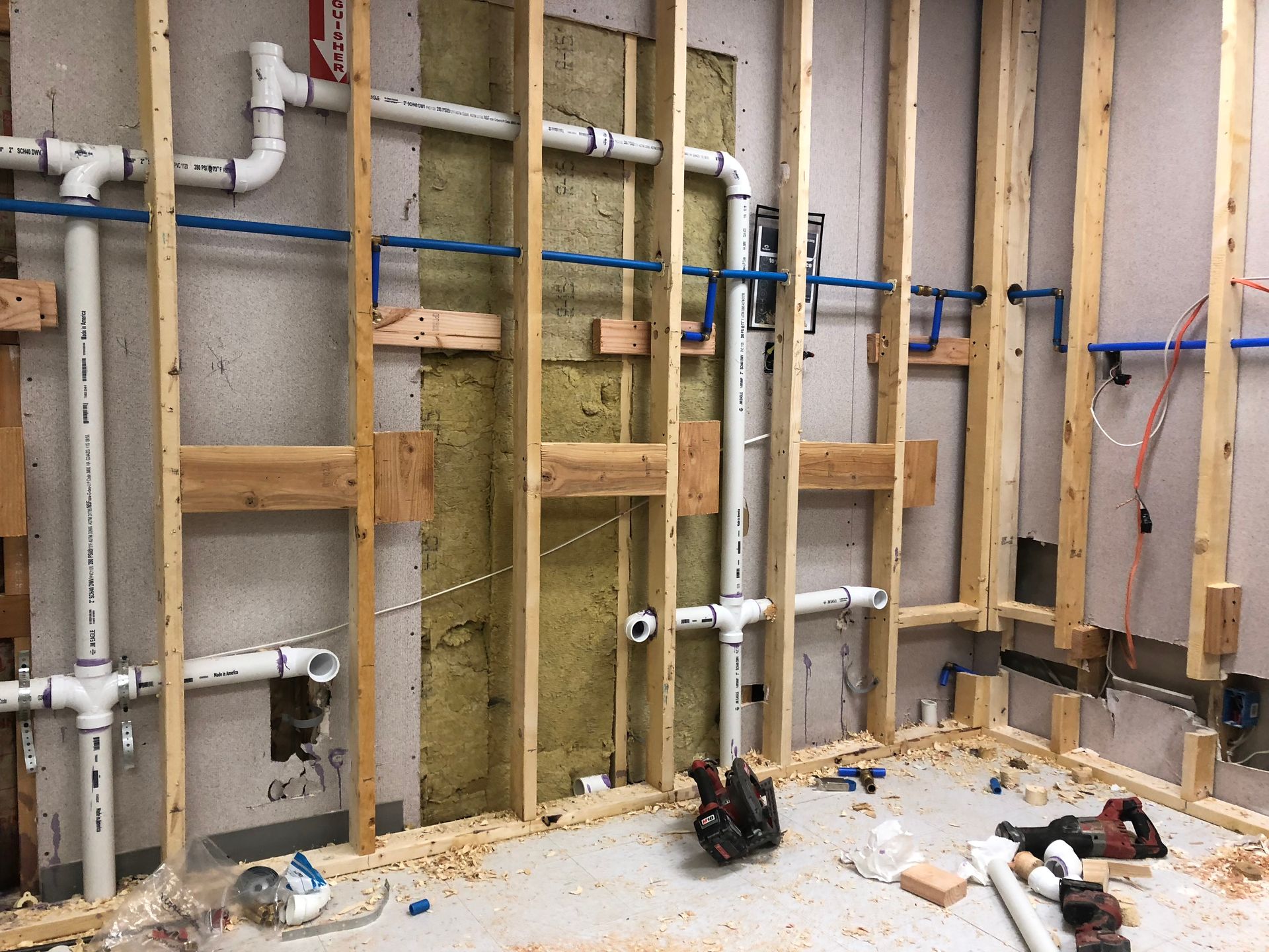 A room with a lot of pipes and a fire extinguisher on the wall