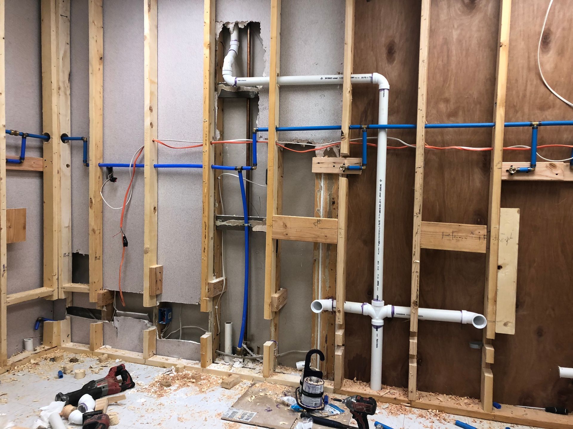 A bathroom under construction with a lot of pipes coming out of the wall.
