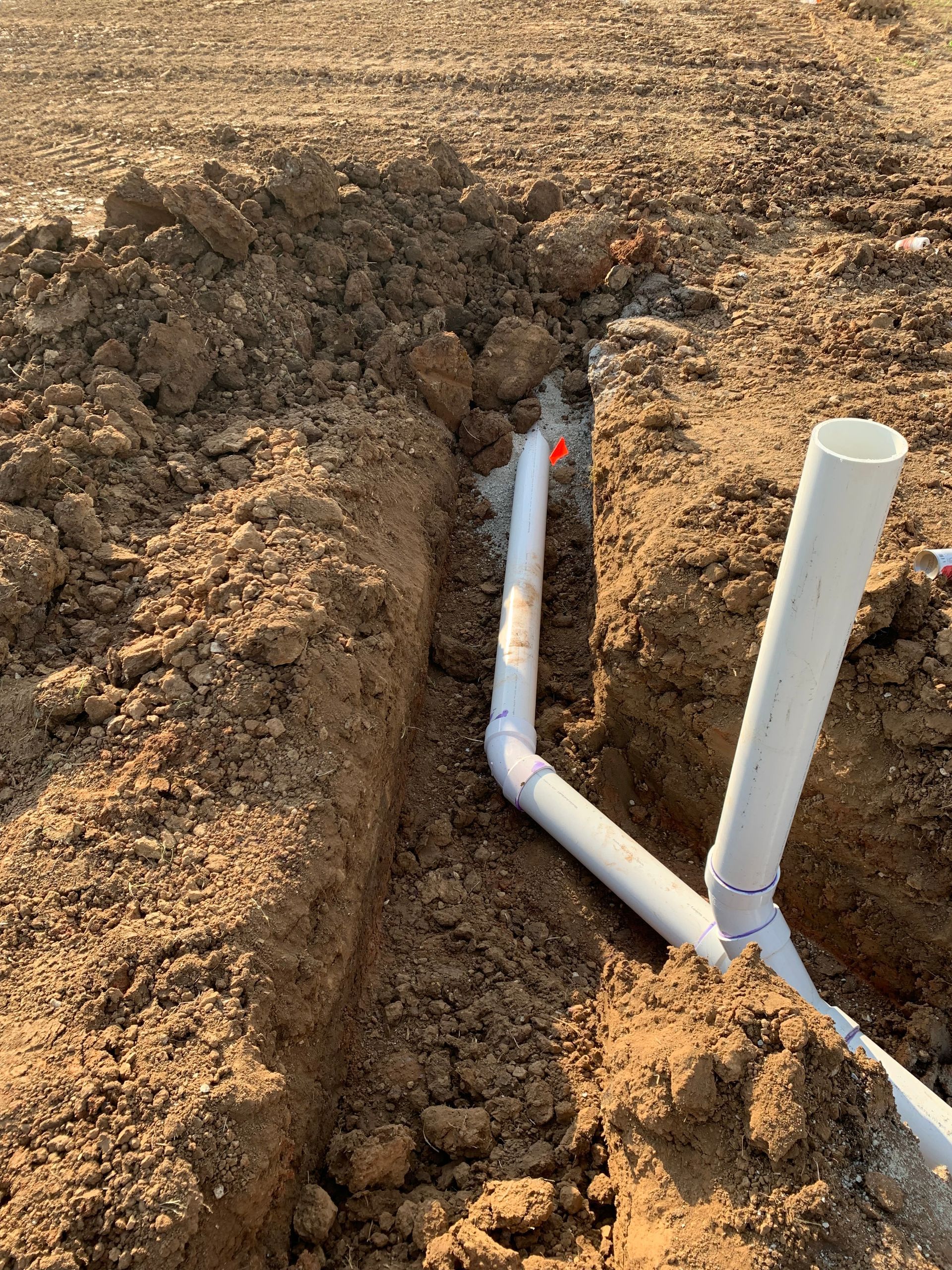 A white pipe is sitting in the middle of a dirt field.