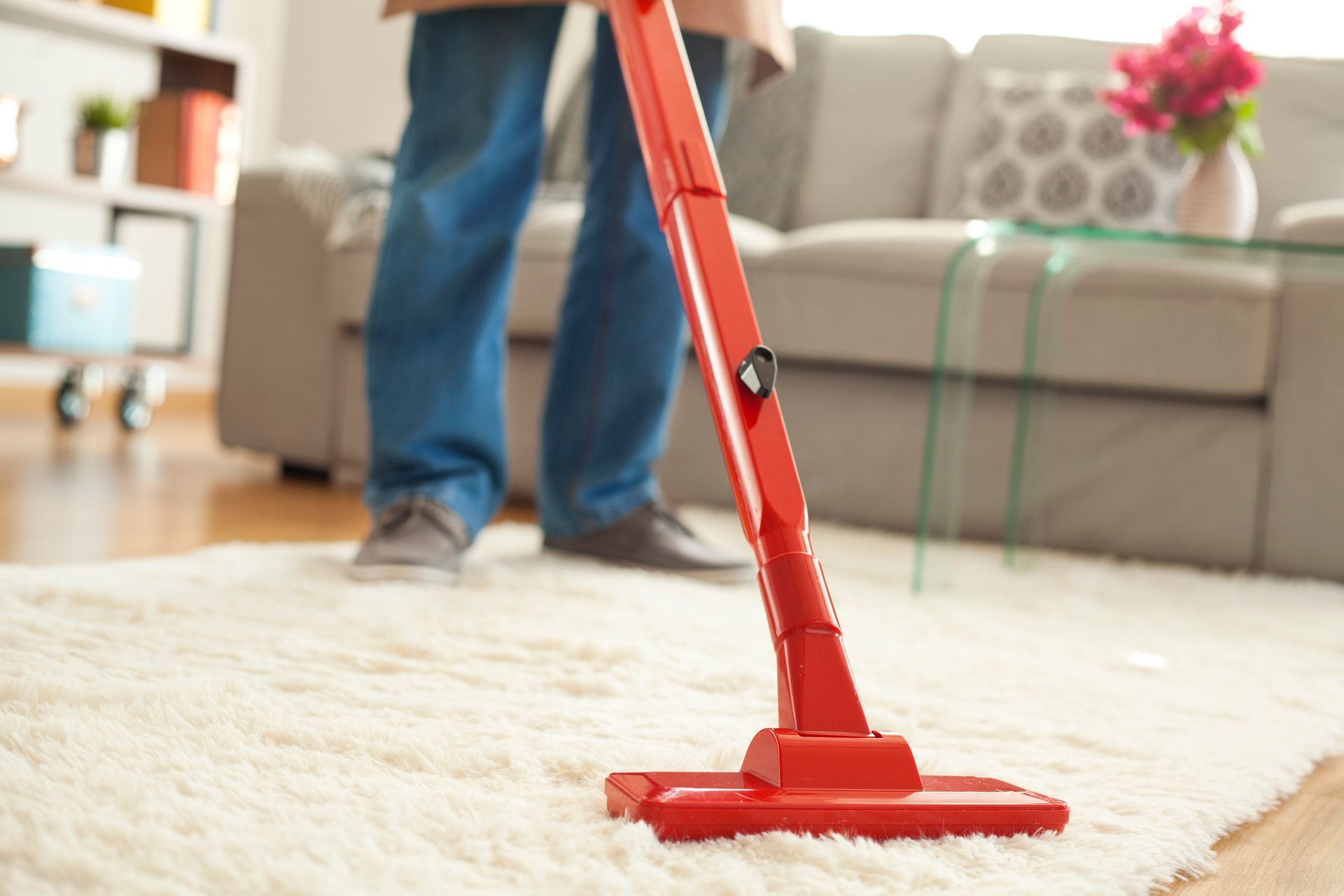 A man using a vacuum cleaner for carpet cleaning in a residential living room setting