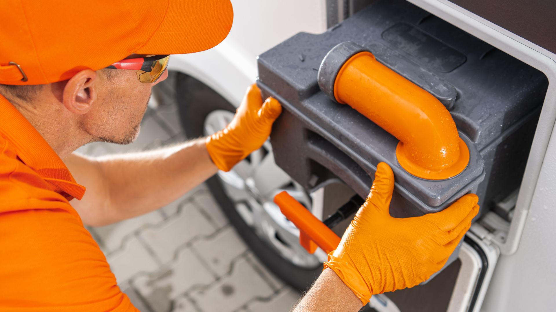 A man wearing orange gloves is working on a camper.