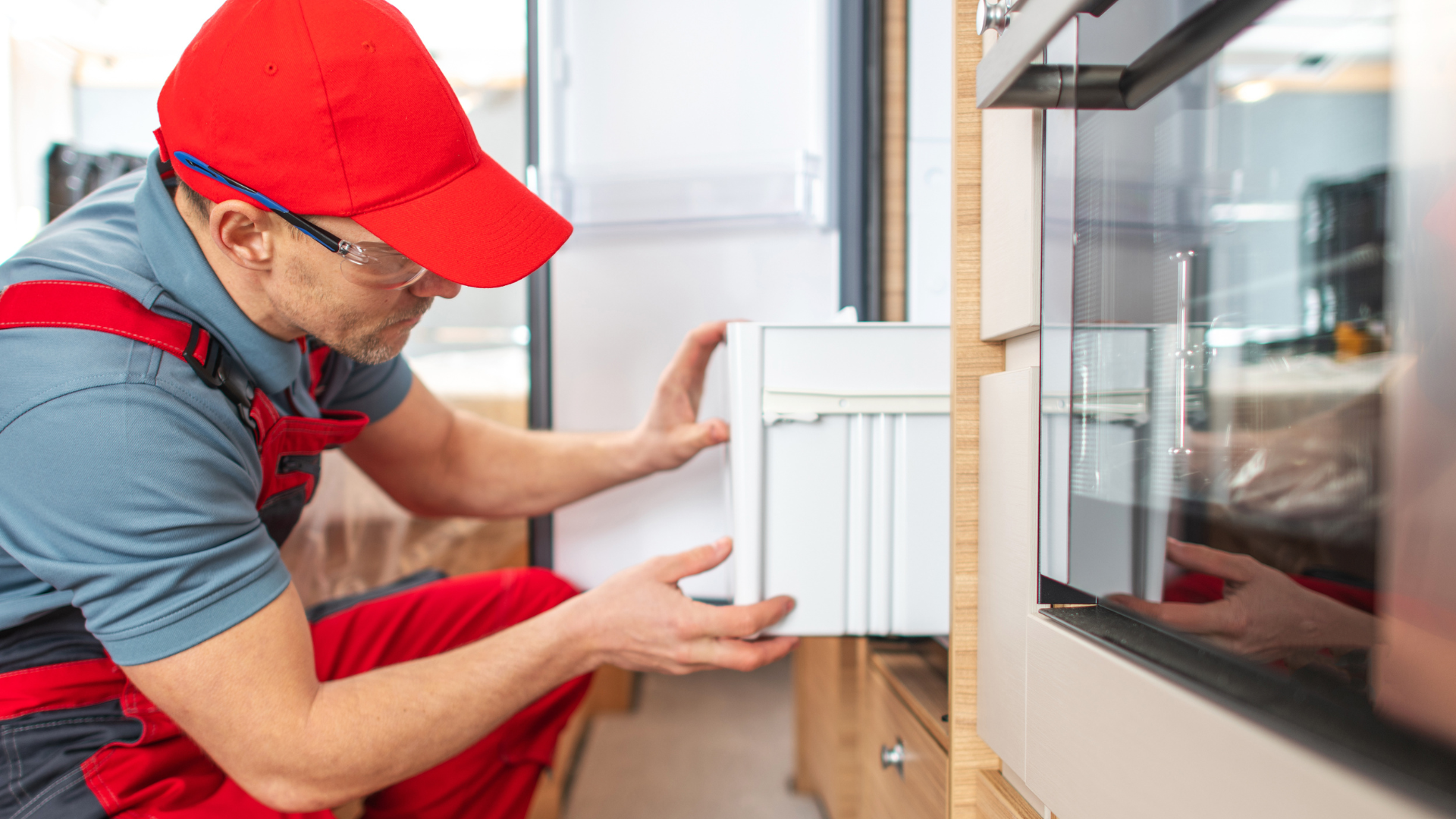 A man is working on a refrigerator in a kitchen.