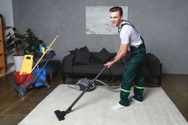 A man is vacuuming a carpet.