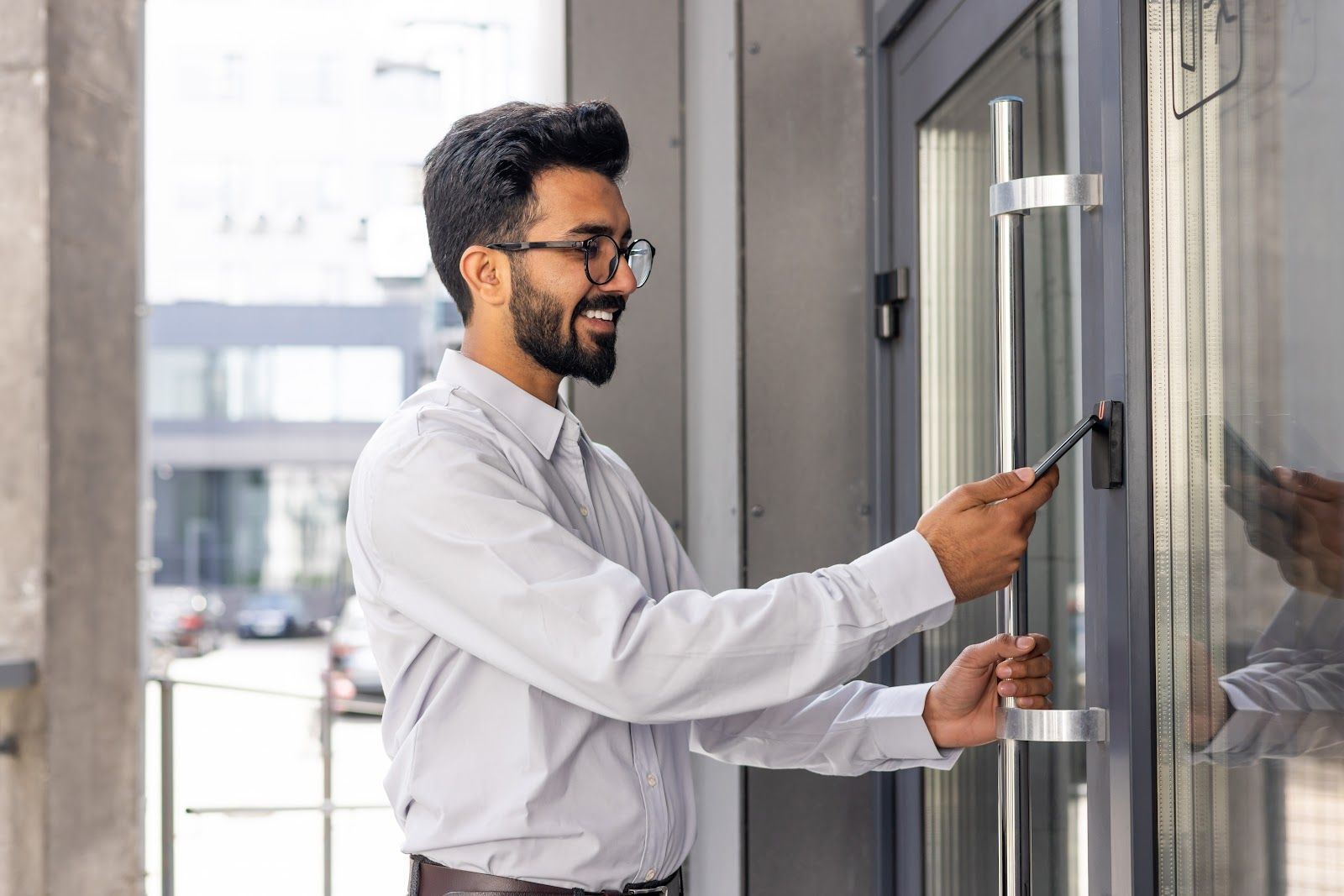 Man unlocking a glass door with a key at an office entrance