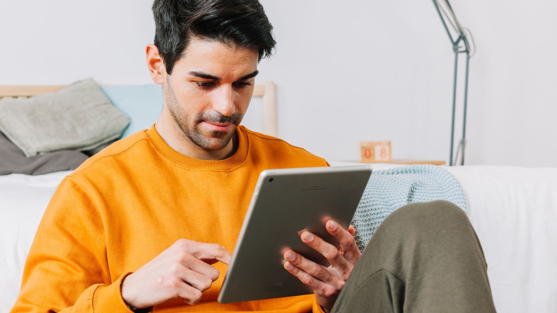 A man is sitting on a couch using a tablet computer.