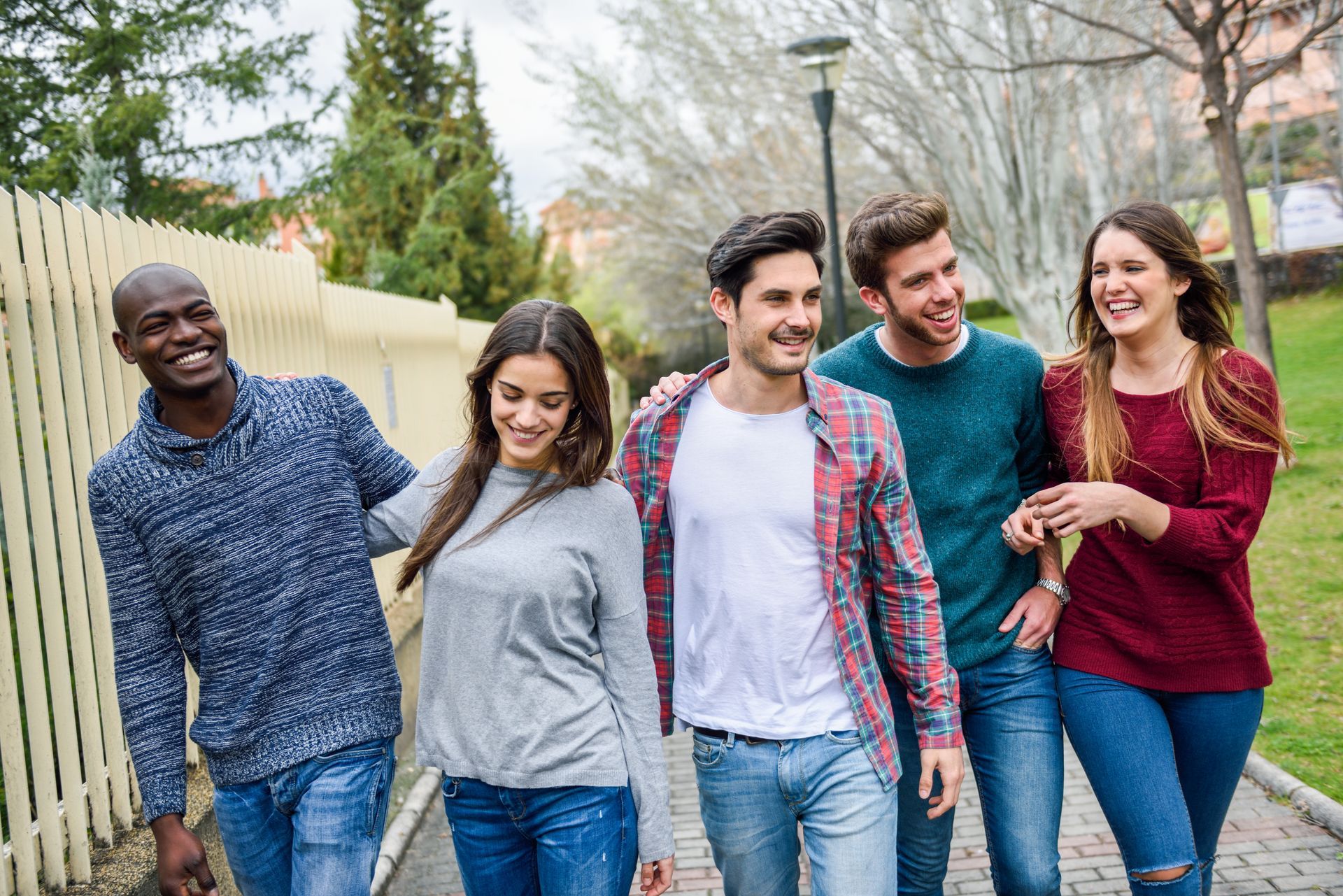 A group of young people are walking down a sidewalk.