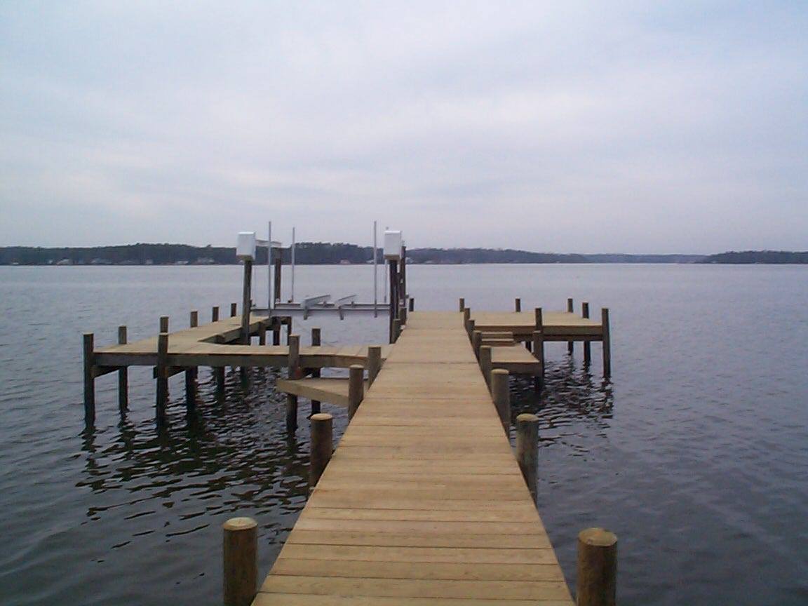 Wooden pier extending into calm water, cloudy sky overhead.