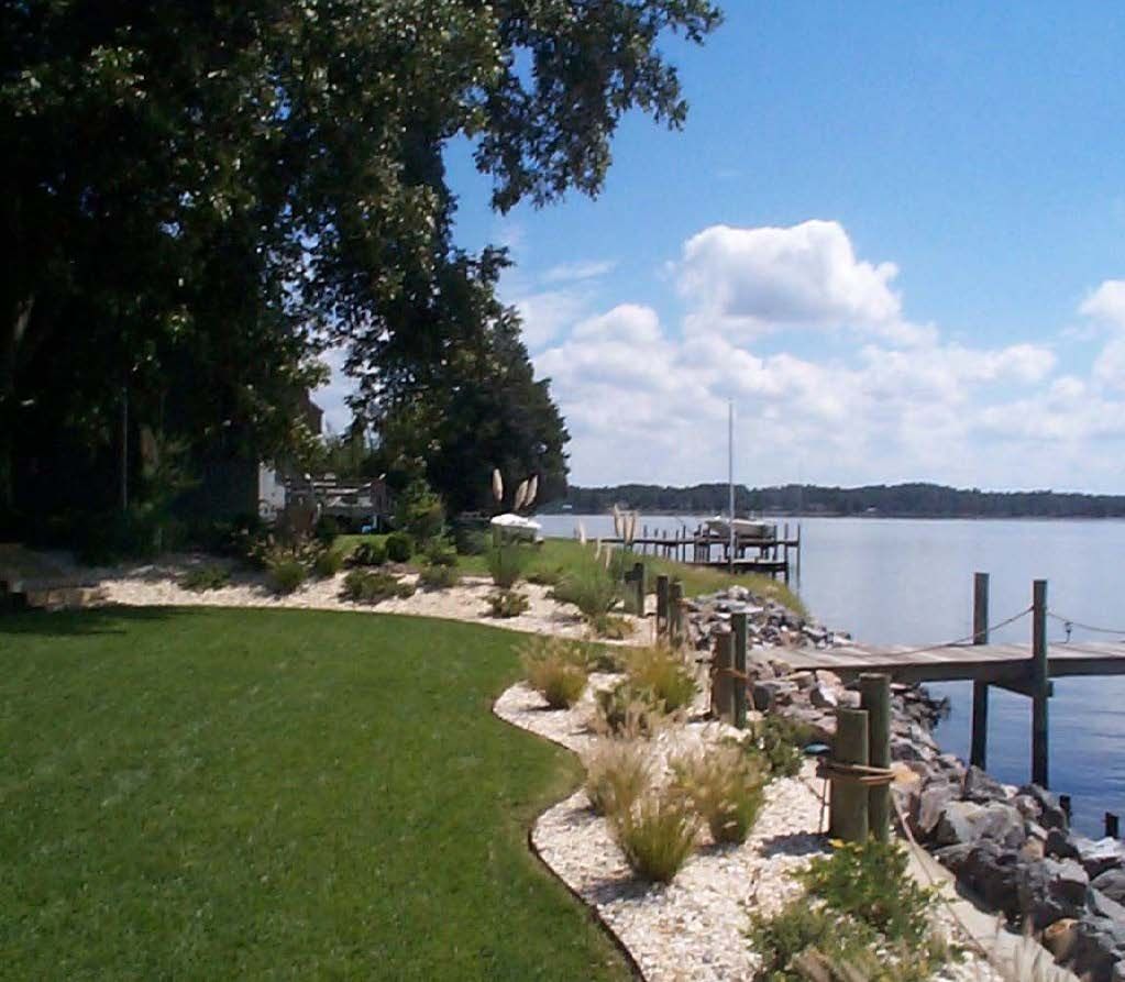 Waterfront landscape design with riprap shoreline, native grasses, and lawn beside a dock.