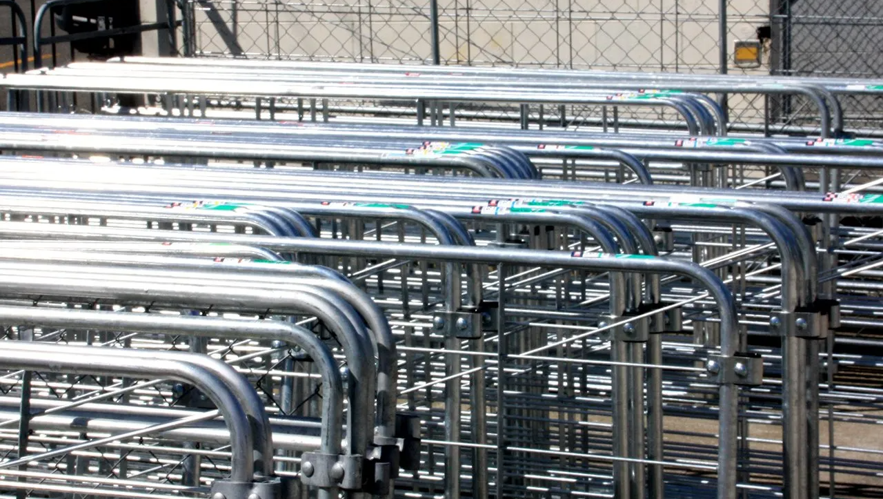 A stack of silver metal crowd control barricades arranged in rows.
